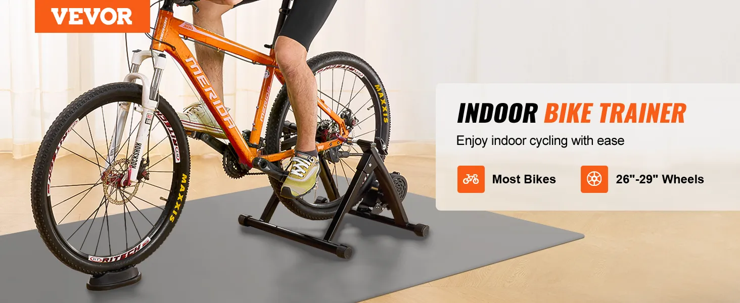 cyclist using VEVOR bike trainer stand for indoor training with orange bike on a training mat.