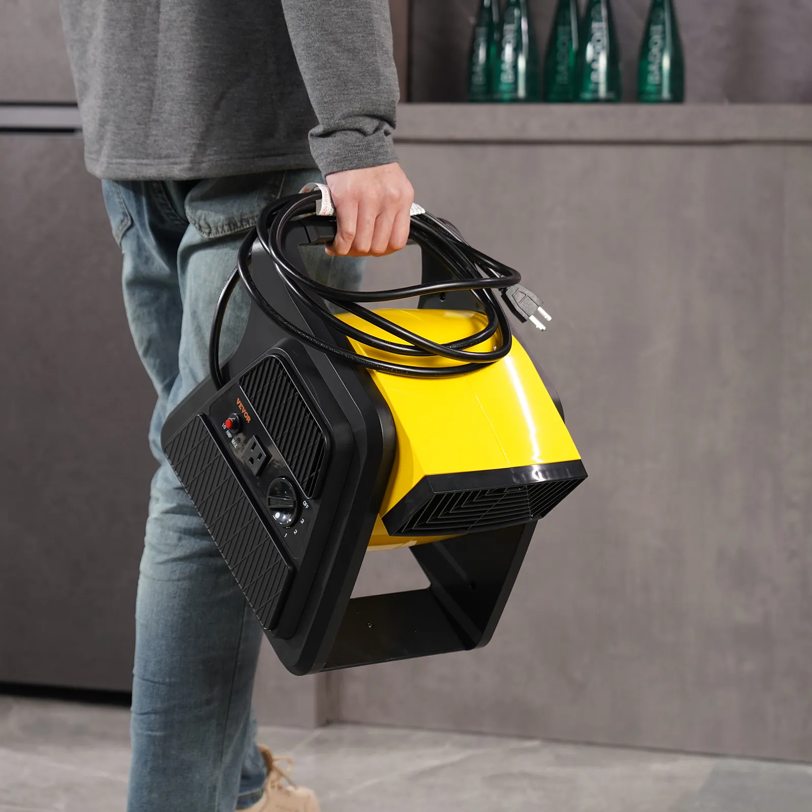 Persona que lleva un ventilador utilitario VEVOR amarillo con un cable negro enrollado a su alrededor en un entorno interior moderno.