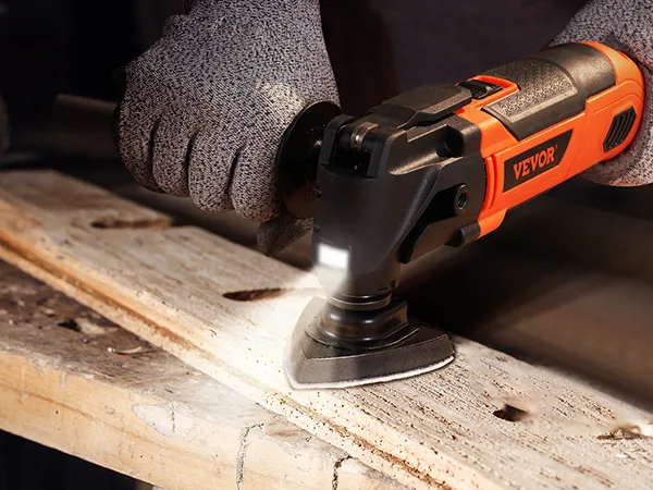 person using VEVOR oscillating tool with gloves on a wooden surface in a workshop.