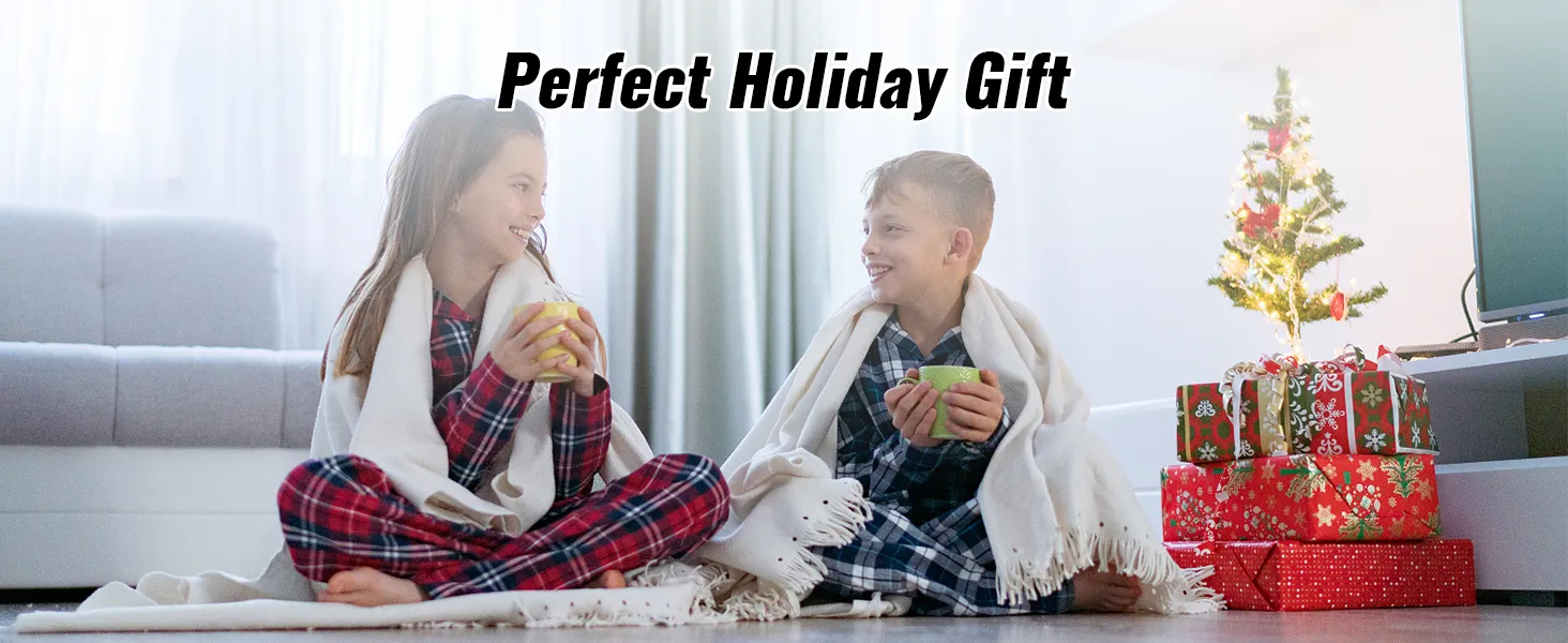 Niños con pijamas a cuadros disfrutan de bebidas cerca de un árbol de Navidad con regalos etiquetados como "regalo navideño perfecto".
