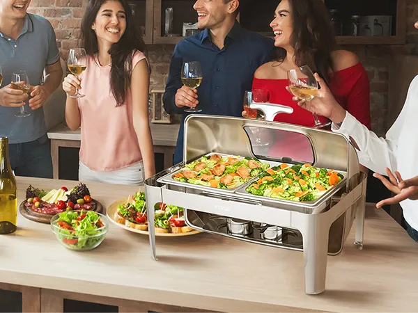 people enjoying food and drinks around a VEVOR chafing dish filled with hot appetizers at a gathering.